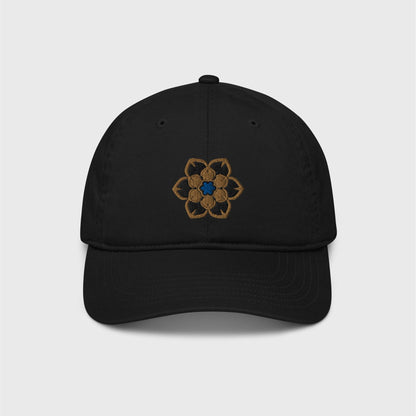 A classic black cap featuring an embroidered logo in the shape of the Wanderer's hat, a gold 6 point hexagonal frame around a filled in black with another gold filled shaped inside and a blue figure in the centre.