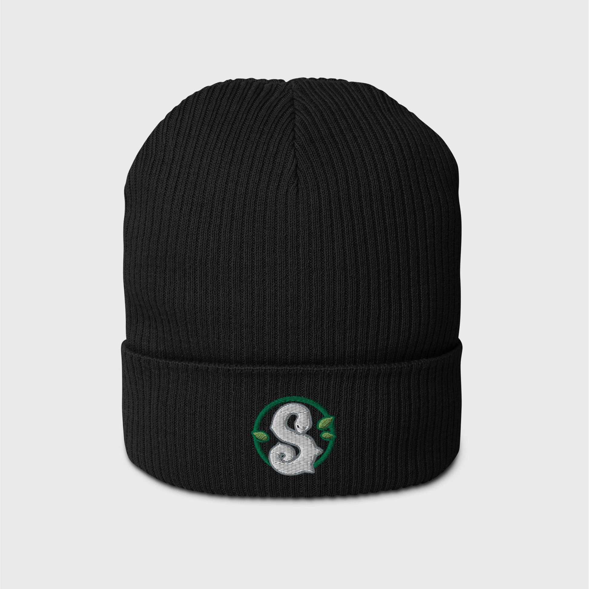 A black ribbed beanie featuring a round dark green frame enclosing a white snake in the shape of an S in the centre. Three small green leaves ornament the frame around the snake.