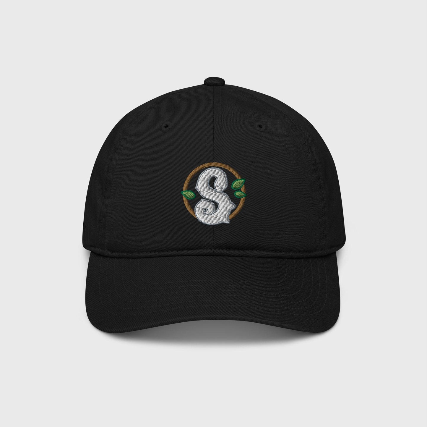 A black classic cap featuring a round dark green frame enclosing a white snake in the shape of an S in the centre. Three small green leaves ornament the frame around the snake.