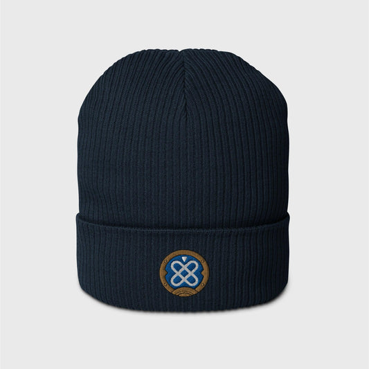 A navy blue ribbed beanie featuring an embroidered round logo of Freminet's diving helmet, in blue with a white round shapes crossed in the centre and a round gold border around it.