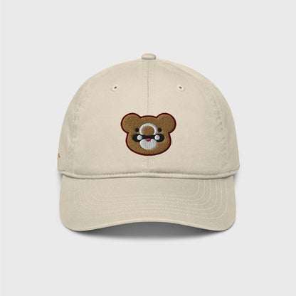 A classic beige cap featuring an embroidered bear head shape of Gouda in gold, with black and white marks and lined in dark red.