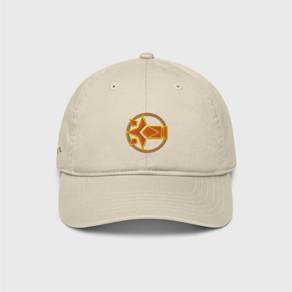 A beige classic cap featuring an embroider logo of Chevreuse ability in orange with yellow lines surrounded by a gold circle frame. You can see a hint of gold letters appearing on the left side of the cap