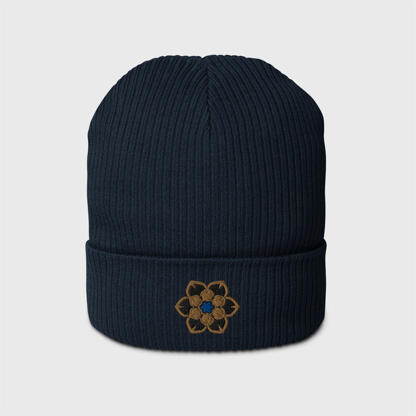 A navy blue ribbed beanie featuring an embroidered logo in the shape of the Wanderer's hat, a gold 6 point hexagonal frame around a filled in black with another gold filled shaped inside and a blue figure in the centre.