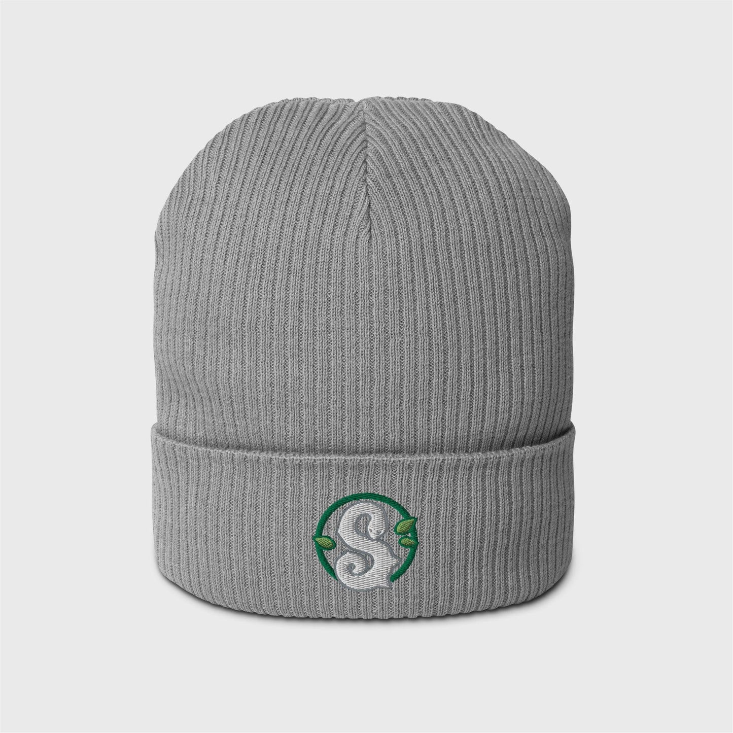 A light grey ribbed beanie featuring a round dark green frame enclosing a white snake in the shape of an S in the centre. Three small green leaves ornament the frame around the snake.