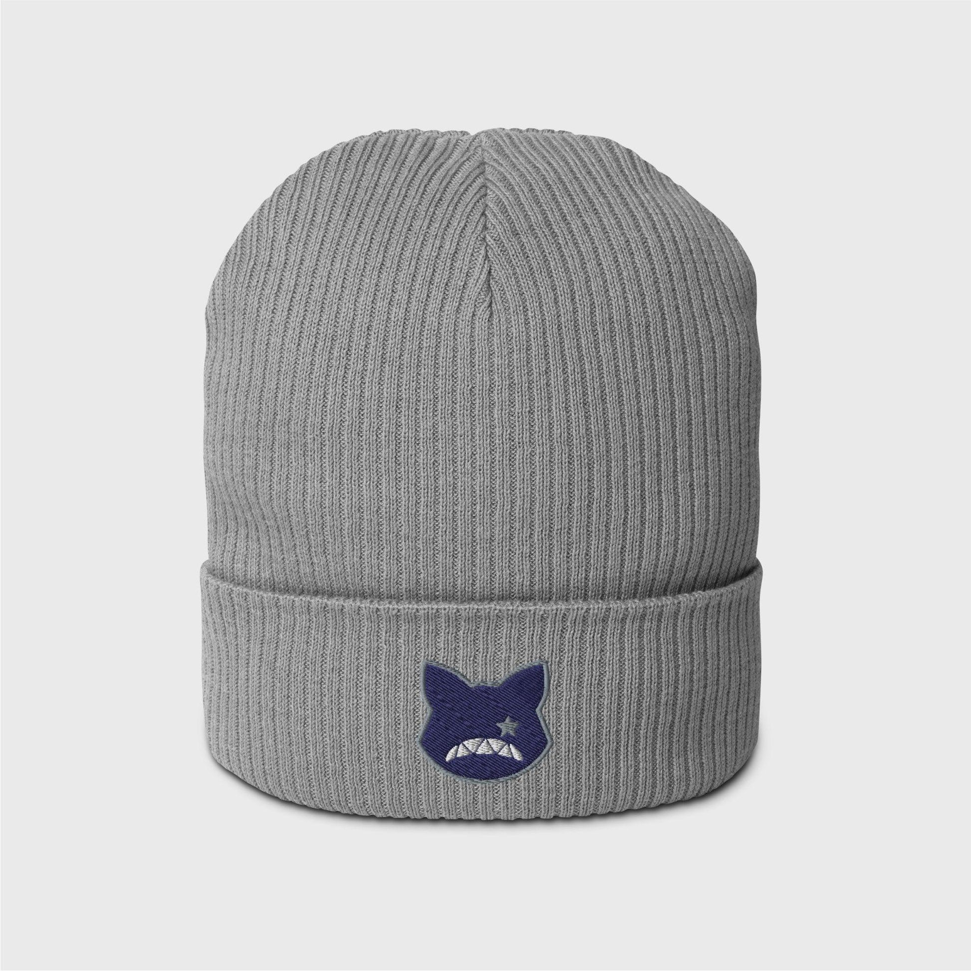 A light grey ribbed beanie featuring an embroidered navy logo shaped as a cat’s head, lined in grey, showing only a right grey eye the shape of a star and a upside down fanged white smile.