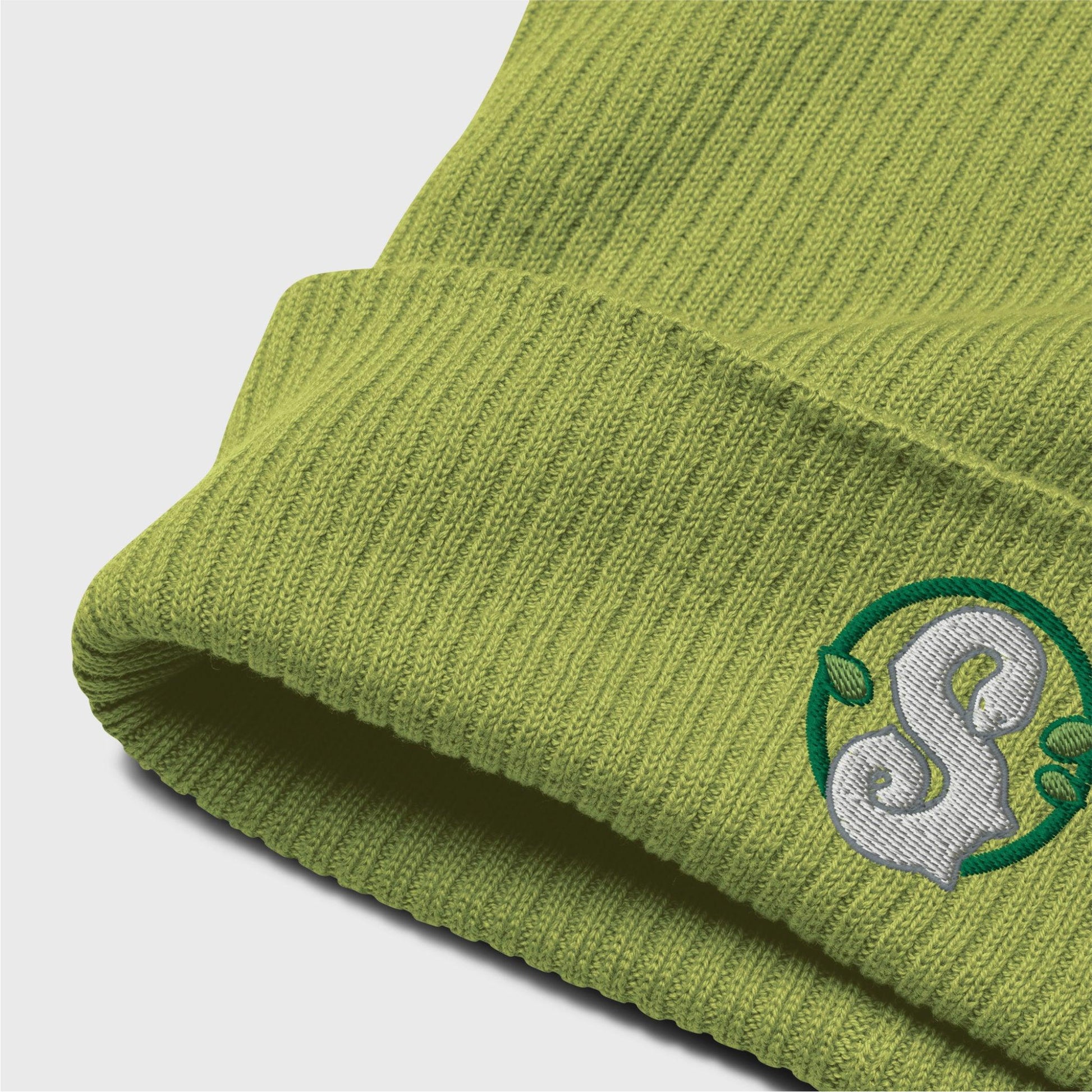 A detailed picture of the ribbed beanie showing the embroidered logo up close. you can see the organic cotton texture of the beanie folded up