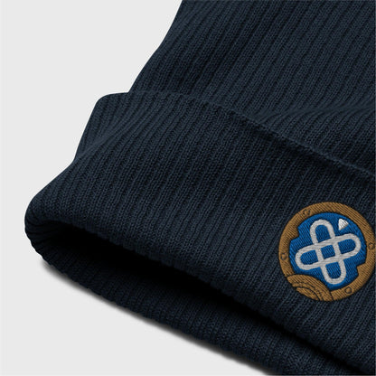 A detailed picture of the ribbed beanie showing the embroidered logo up close. you can see the organic cotton texture of the beanie folded up