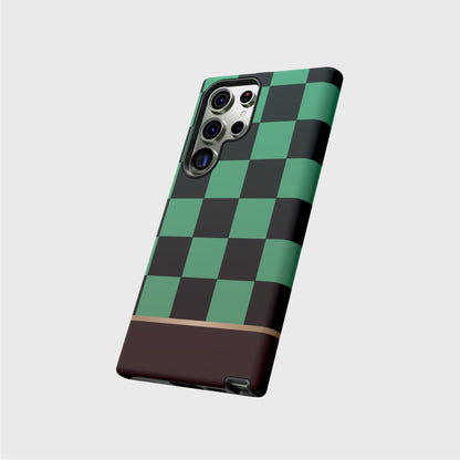 A tough Samsung case featuring Tanjiro’s black and green checkered kimono pattern. A gold division 3/4 vertically from the bottom separates the pattern from a brown base.