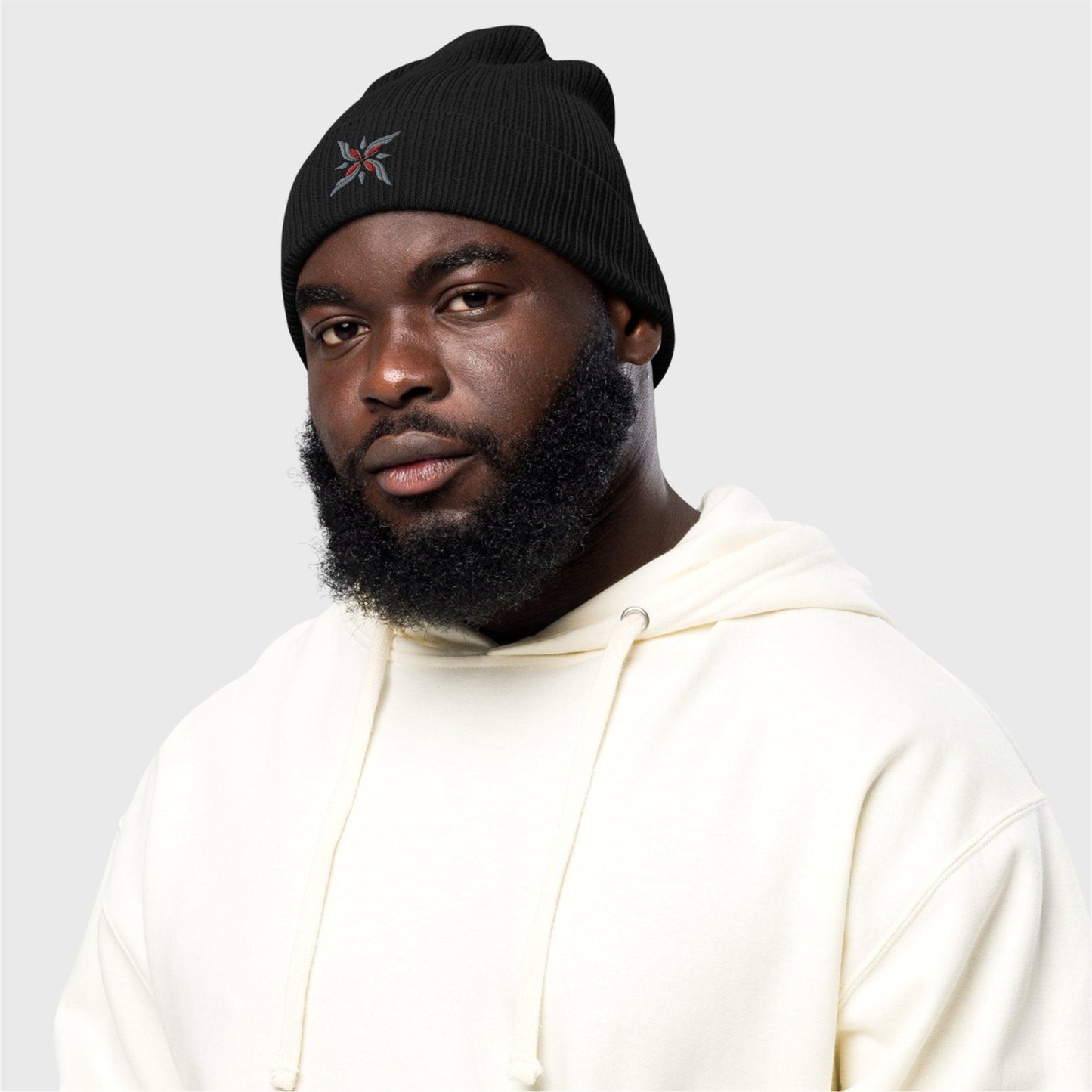 A close up of a man looks at the camera wearing the black beanie featuring the logo on the front.