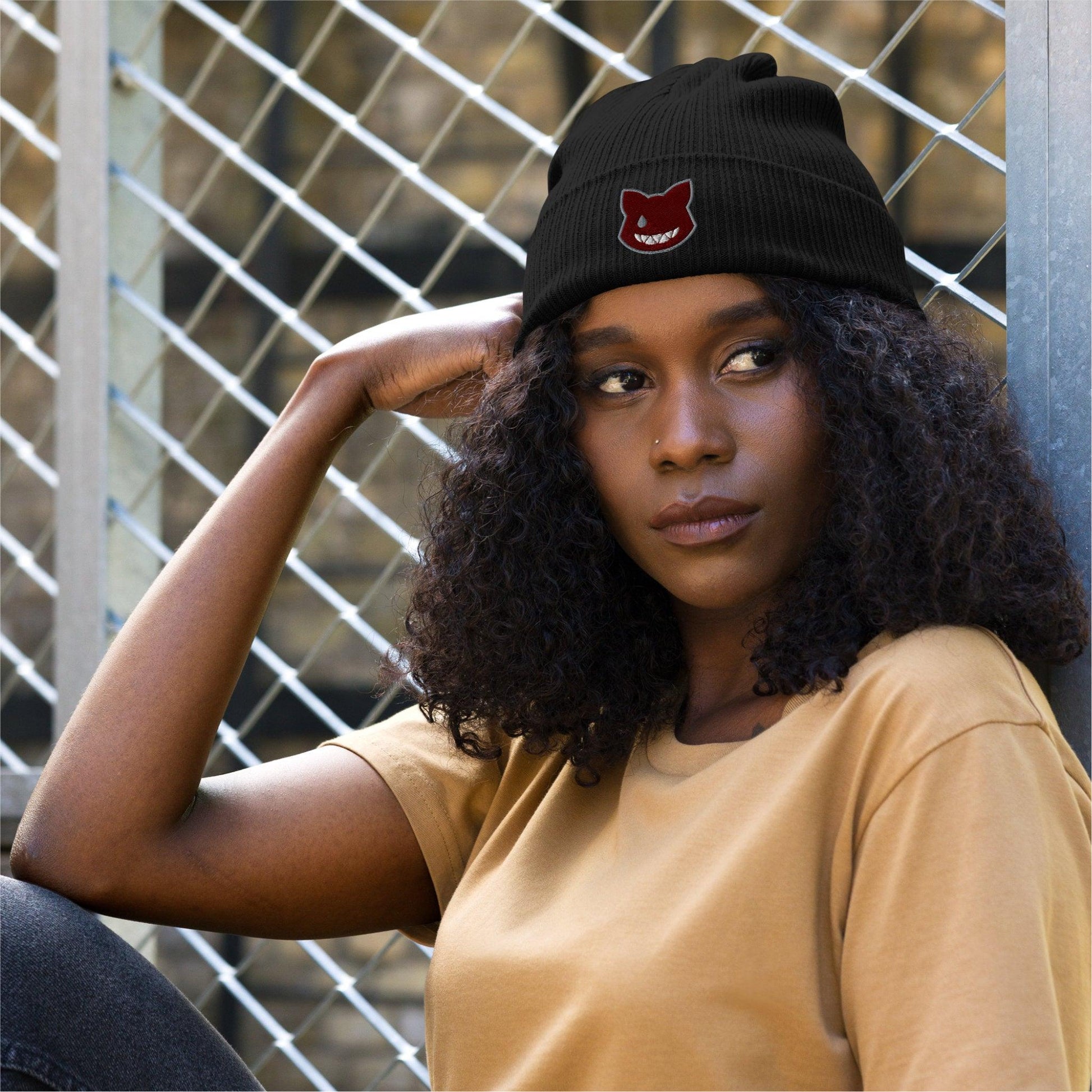 A close up of a woman looking right from the camera wears the black beanie featuring the logo at the front.